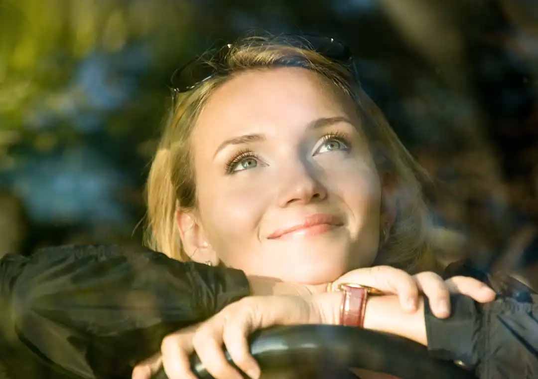 Happy woman leaning on steering wheel